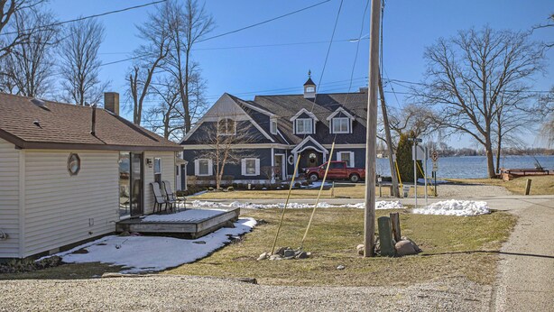 A two-story house with a garage, a driveway, and a dock extending into a lake. - Beautiful 2 bed cottage by Coldwater Lake! (Coldwater)