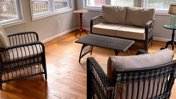 A spacious room with a large window, a sofa, two wicker chairs, and a small table. - Lynchburg Family Living - close to Liberty University and dining options (Lynchburg)
