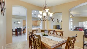 A spacious dining area with a marble table, wooden chairs, and a chandelier. - Golfer's Oasis w/ Heated Pool in Avondale! (Avondale)