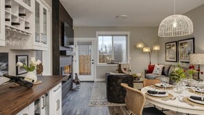 A modern kitchen with white cabinets, a wooden countertop, and a dining area with a round table set for six. - All New! Maison Monroe in Carlton (Carlton)