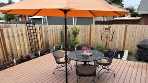 A wooden deck with a round table and chairs, an orange umbrella, and a decorative horse wheel. - All New! Maison Monroe in Carlton (Carlton)