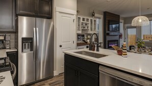 A modern kitchen with stainless steel appliances, a white countertop, and dark cabinetry. - All New! Maison Monroe in Carlton (Carlton)
