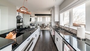Una cocina moderna con una isla central, electrodomésticos de acero inoxidable y ventanas amplias que permiten la entrada de luz natural.