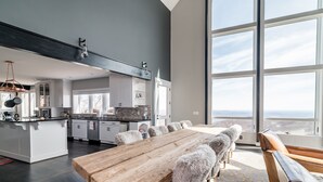Una cocina moderna con una isla grande, armarios blancos y vistas amplias a través de grandes ventanas.