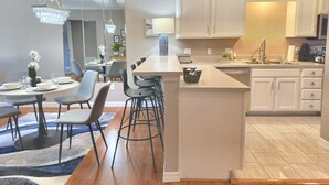 A modern kitchen with white cabinets, a central island, bar stools, and a chandelier. - 3 Pools, Hot Tub, Sports Courts, Resort, Golf, Gorgeous All New Condo! (Branson)