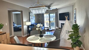 A modern living room with a dining area, a chandelier, a fireplace, and a view of the outside balcony. - 3 Pools, Hot Tub, Sports Courts, Resort, Golf, Gorgeous All New Condo! (Branson)
