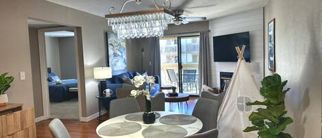 Uma sala de estar moderna com área de jantar, um candelabro, lareira e vista para a varanda.