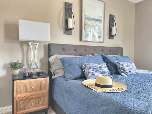 Un dormitorio ordenado con cama, mesitas de noche, lámpara y cuadros en la pared.