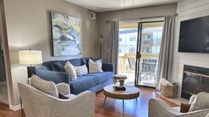 A modern living room with a blue sofa, two armchairs, a coffee table, and a fireplace. - 3 Pools, Hot Tub, Sports Courts, Resort, Golf, Gorgeous All New Condo! (Branson)