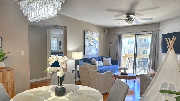 A modern living room with a dining area, a chandelier, a ceiling fan, and a view to the outside. - 3 Pools, Hot Tub, Sports Courts, Resort, Golf, Gorgeous All New Condo! (Branson)