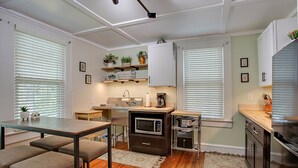 Una cocina compacta con zona de comedor, suelo de madera y electrodomésticos integrados.