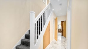 A modern interior with a staircase, wooden doors, and a marble floor.