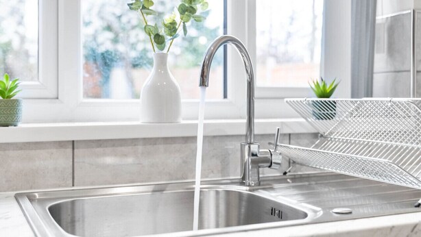 A modern kitchen with a stainless steel sink, a faucet, and a wire rack.