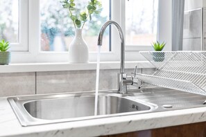 A modern kitchen with a stainless steel sink, a faucet, and a wire rack. - 4-bedroom townhouse in Harborne (Harborne)
