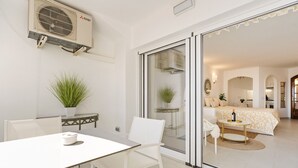 A modern room with a sliding glass door leading to a living area, a small table with a plant, and a white chair. - WELCS ESTUDIO 057 EMP Frente al Mar (Empuriabrava)