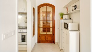 A kitchen with white cabinets, a wooden door, a microwave, and a toaster. - WELCS ESTUDIO 057 EMP Frente al Mar (Empuriabrava)
