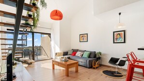 A modern living room with a wooden coffee table, a grey sofa with colorful cushions, a red chair, and two framed artworks on the wall. - WELCS APARTAMENTO 216 EMP Frente con Terraza (Empuriabrava)