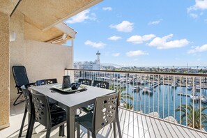 A balcony with a table and chairs overlooking a marina with boats and a distant tower. - WELCS APARTAMENTO 216 EMP Frente con Terraza (Empuriabrava)
