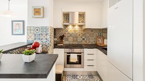 A modern kitchen with white cabinets, a stainless steel oven, and patterned tile backsplash. - WELCS APARTAMENTO 216 EMP Frente con Terraza (Empuriabrava)