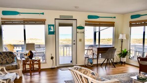 Ein Zimmer mit Blick auf den Strand, ausgestattet mit Korbmöbeln, einem Schreibtisch und einer Lampe.
