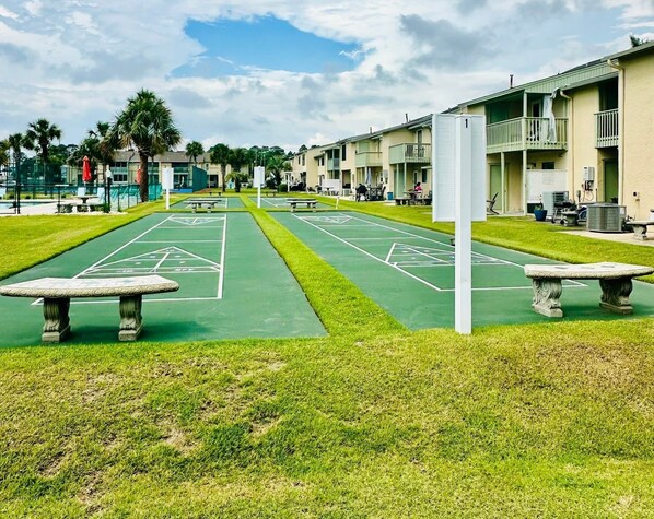 A courtyard with a shuffleboard court, outdoor seating, and a row of buildings with balconies. - Pool in Backyard and steps to beach (Panama City)