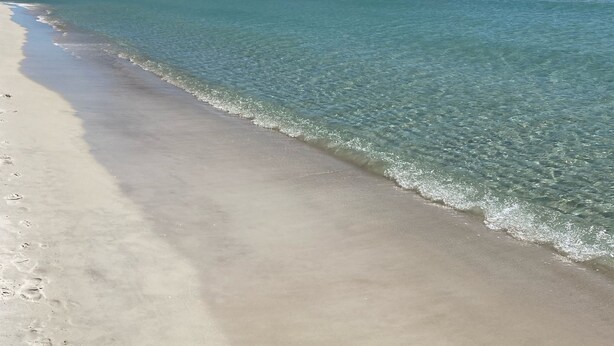 A beach with clear water and a sandy shore. - Pool in Backyard and steps to beach (Panama City)