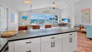 A modern kitchen with a large island, white cabinetry, and pendant lighting. - Bayfront Home with Amazing Water Views! Private pool! – Breakaway (Anna Maria)