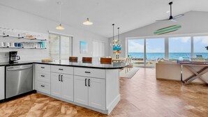 A modern kitchen with a large island, white cabinetry, and a view of the ocean. - Bayfront Home with Amazing Water Views! Private pool! – Breakaway (Anna Maria)
