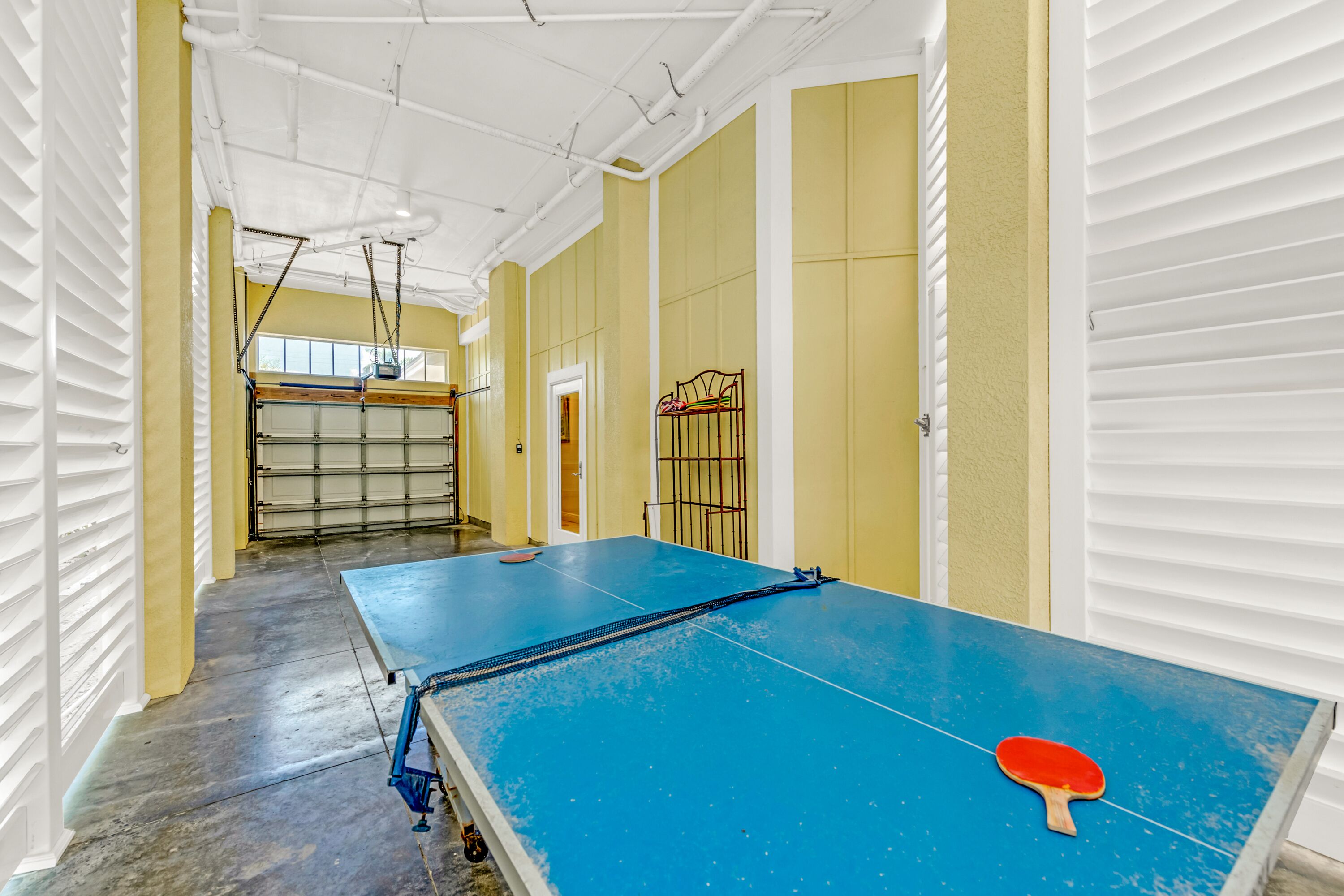A ping pong table in a room with yellow walls and white blinds.