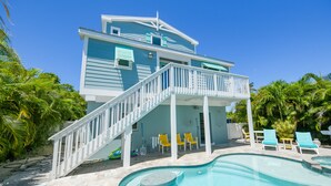 Un bâtiment à deux étages doté d’une piscine, d’une terrasse couverte et de plusieurs chaises longues.