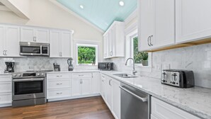 Une cuisine moderne avec des meubles blancs, des appareils en acier inoxydable et un plancher en bois.