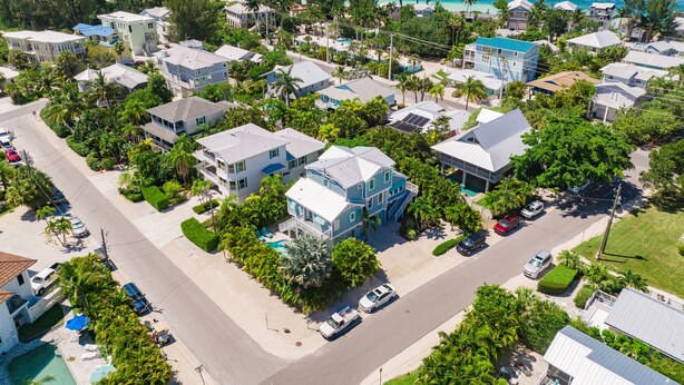 Vue aérienne d’une zone résidentielle côtière, avec des maisons, des routes et une plage.
