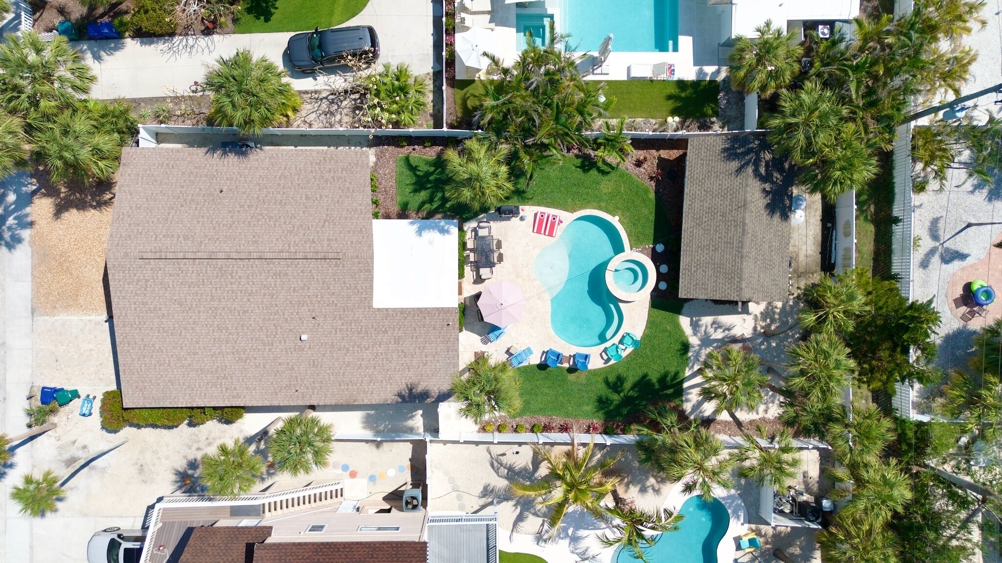 Vista aérea de uma propriedade residencial com piscina, móveis de pátio e palmeiras.