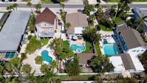Vista aérea de una zona residencial con varias casas, una piscina y palmeras.