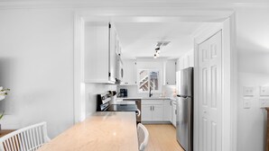 Una cocina moderna con armarios blancos, encimera de mármol y electrodomésticos de acero inoxidable.