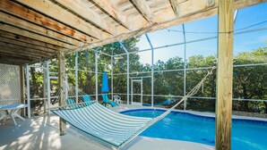 A pool area with a hammock, lounge chairs, and a covered patio. - Canal Front Home with Dock, Saltwater Pool, Ping Pong - Ama Maria (Anna Maria)