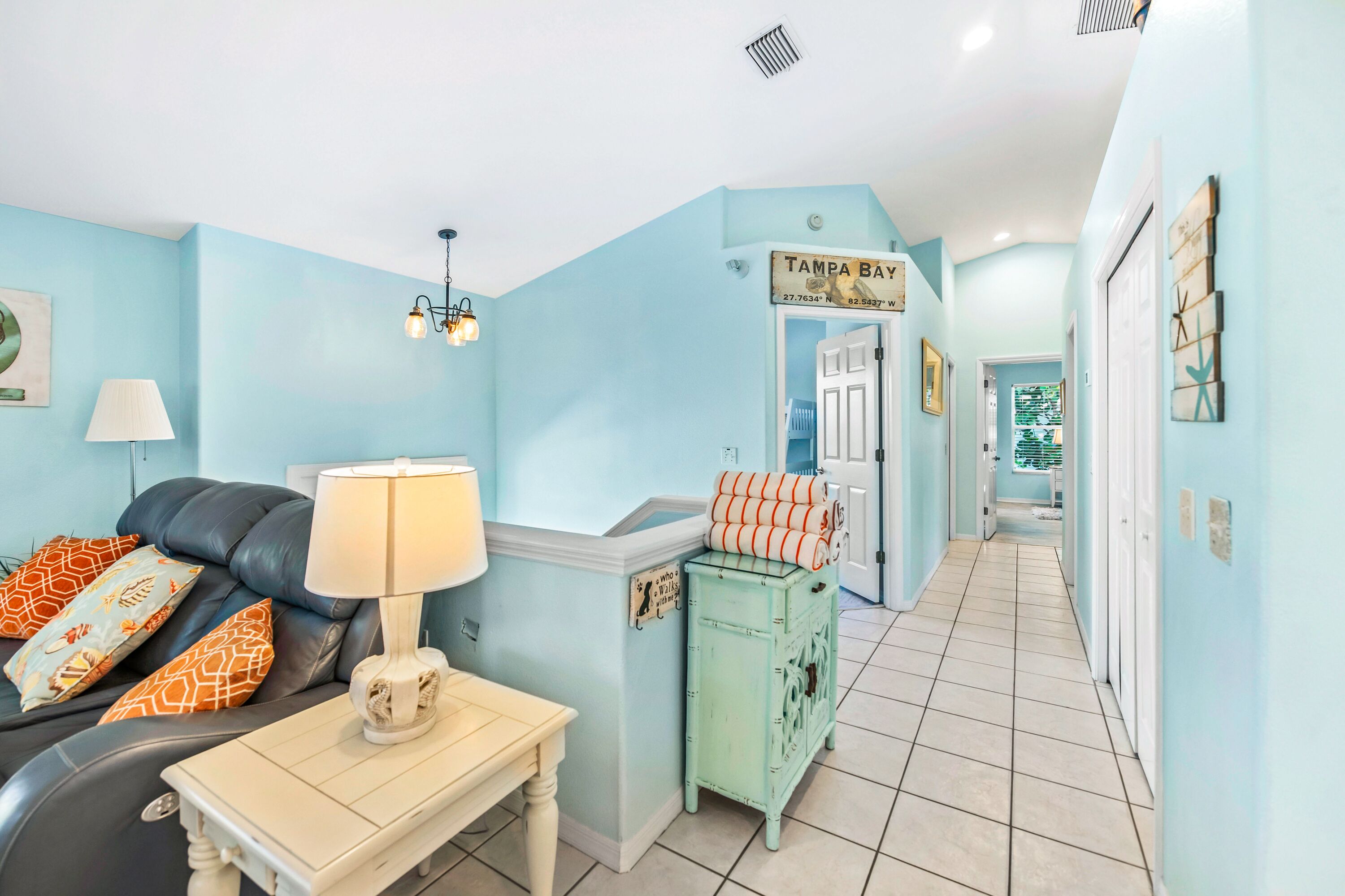 A living room with a sofa, a lamp, a small table, and a sign reading "Tampa Bay".