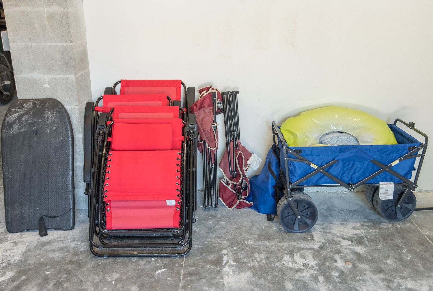 Ein Gepäckwagen mit blauer Abdeckung, einem roten Koffer und einem schwarzen Koffer.