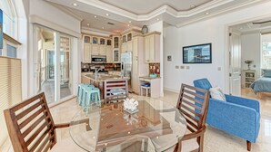 A spacious living room with a glass coffee table, wooden chairs, and a blue sofa.