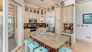 A spacious kitchen with granite countertops, stainless steel appliances, and a large island with bar stools.