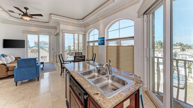 A spacious kitchen with a granite countertop, stainless steel sink, and a ceiling fan.