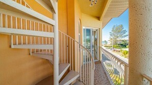 A balcony with a white railing, a spiral staircase, and a view of the outside.