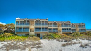 Un hôtel situé en bord de mer, doté de nombreux balcons et donnant sur une plage de sable.
