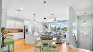 A spacious kitchen with white cabinets, a central island with seating, and a dining table.