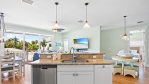 A modern kitchen with a dishwasher, a sink, and a dining area with a table and chairs.