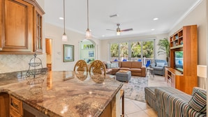 A spacious living area with a large kitchen island, wooden cabinets, and a ceiling fan.
