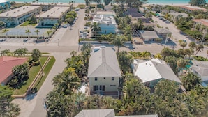 An aerial view of a coastal residential area with multiple buildings, a parking lot, and a beach in the background.