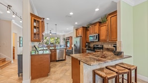 A spacious kitchen with wooden cabinets, a central island, and a built-in microwave.