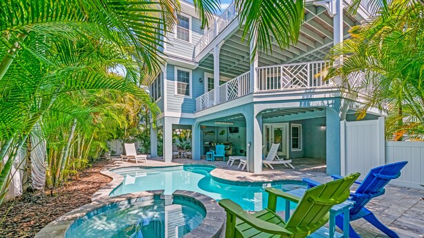 A pool area with multiple swimming pools, lounge chairs, and a covered deck with a view of the pool. - Sunset Views from Rooftop, Heated Pool, Game Room- Caribbean Dream (Holmes Beach)