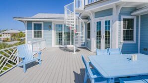 A coastal house with a deck, white railings, and a spiral staircase. - Sunset Views from Rooftop, Heated Pool, Game Room- Caribbean Dream (Holmes Beach)